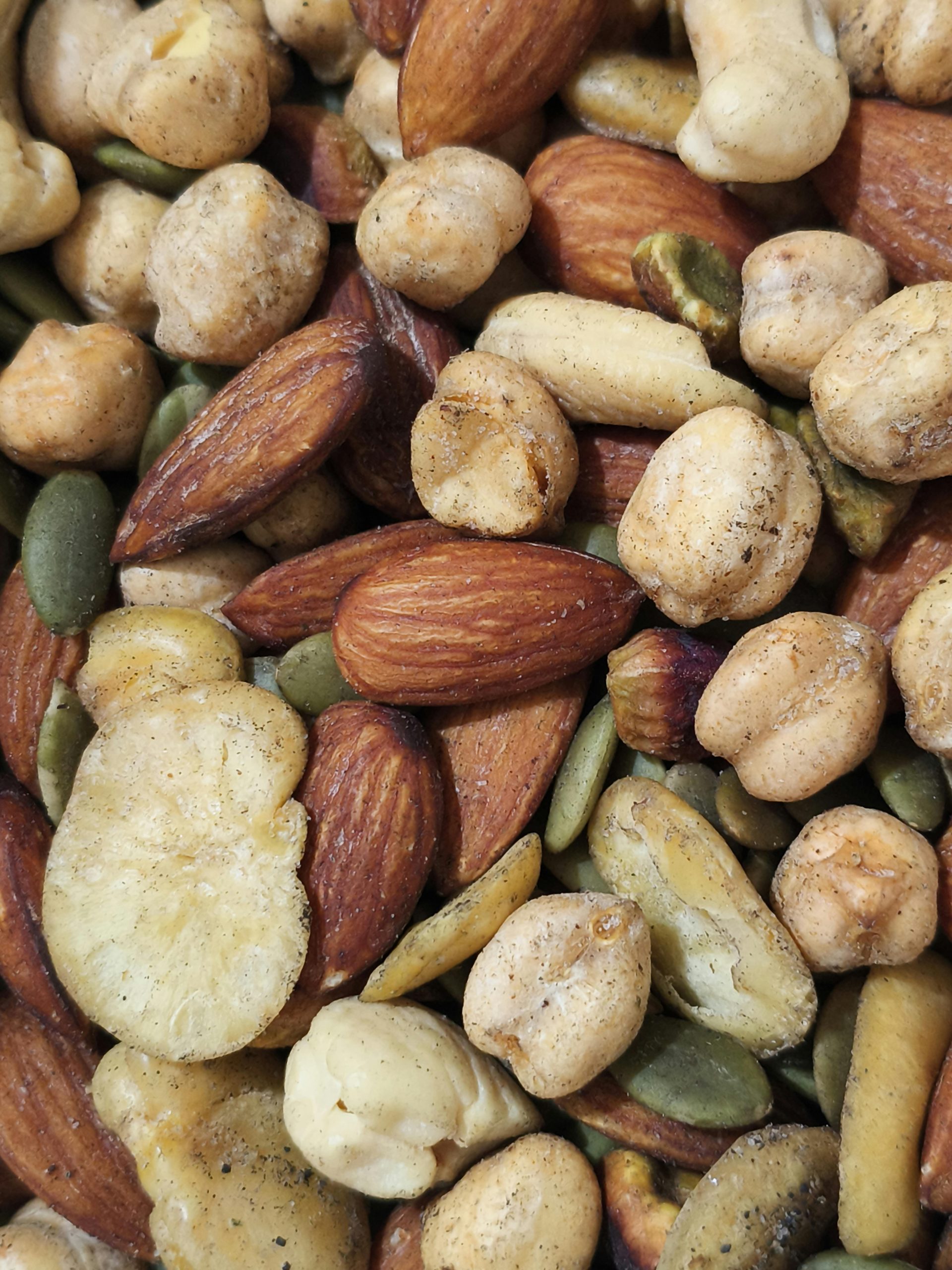 A detailed close-up of mixed nuts and seeds including almonds, cashews, and pumpkin seeds.